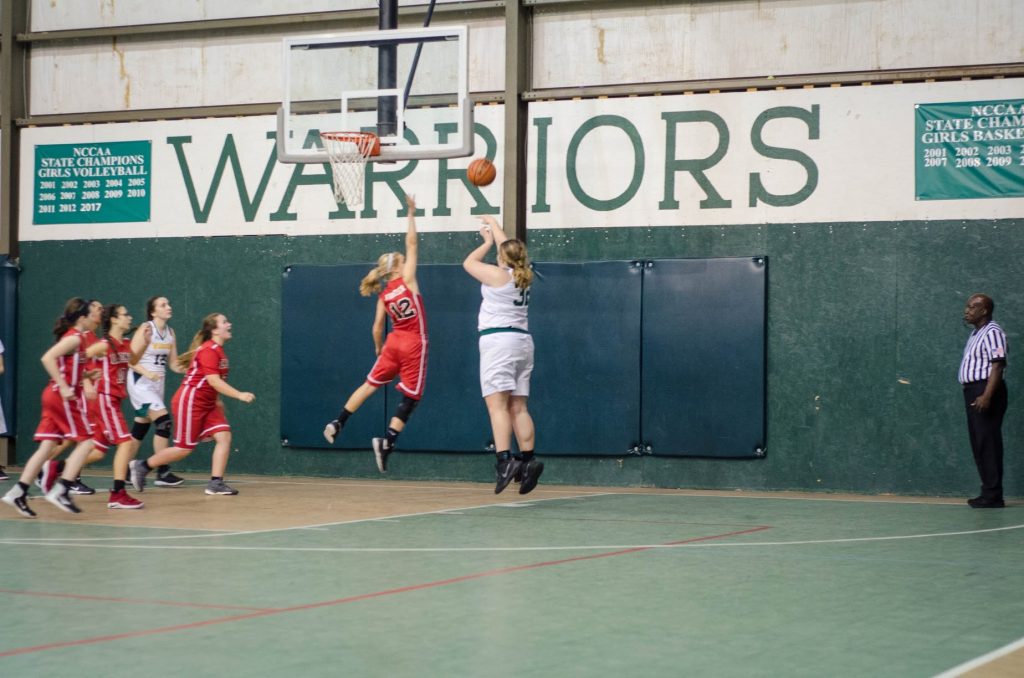 Gramercy Warriors girls basketball player shooting under the WARRIORS banner in the Warriors gym